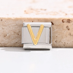 Macro detail of Italian modular charm featuring a golden letter V on stainless steel base