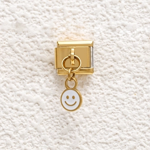 Close-up of golden stainless steel modular charm with a white enamel smiley face pendant