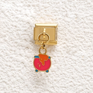 Detailed close-up of a golden stainless steel Italian charm with a colorful potion pot