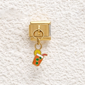 Detail of Italian charm with gold metal base and colorful enamel juice cup pendant