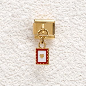 Detail of golden Italian charm with red scalloped edge and raised gold heart on white base
