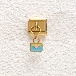 Macro detail of Italian gold charm with colored envelope and pink heart pendant