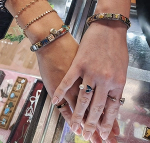 Nahaufnahme von modularem Charm-Armband und Ringstapel auf der Hand am Schaukasten