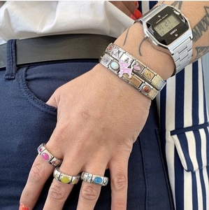 Makro-Detail eines italienischen Charm-Armbands mit Emaille-Icons und bunten Edelsteinen