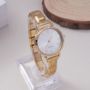Macro view of gold quartz watch dial with Roman numerals and stainless steel strap detail