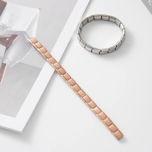 Dettaglio di bracciali elastici modulari in oro rosa e argento con incisione in acciaio inox