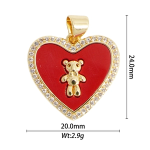 Macro view of gold-plated red enamel heart pendant with bear detail and zircon border