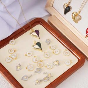 Detalle macro de colgantes de corazón y estrella bañados en oro 18K con nácar y circón