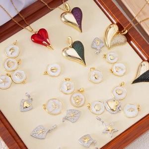 Detalle de colgantes de corazón bañados en oro con esmalte y pedrería en bandeja de joyas