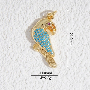 Détail d'un pendentif perroquet doré avec des perles bleues et des pierres rouges sur pierre