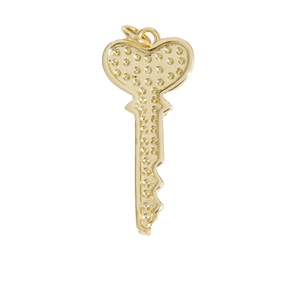 Pendentif clé en forme de cœur doré avec texture à pois sur un fond blanc neutre
