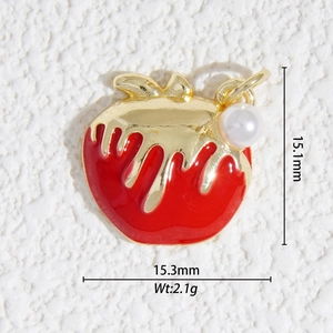 Détail macro du pendentif pomme cœur avec émail rouge, effet doré et une petite perle blanche
