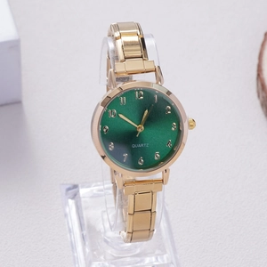 Detailed macro view of a gold alloy watch with a sunray green dial and metal link band
