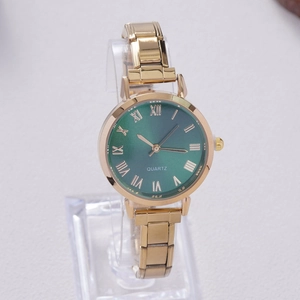 Detail view of gold quartz watch with a sunburst emerald dial and roman numerals