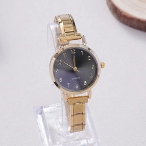 Detailed close-up of a women's gold quartz watch featuring a gray sunburst dial