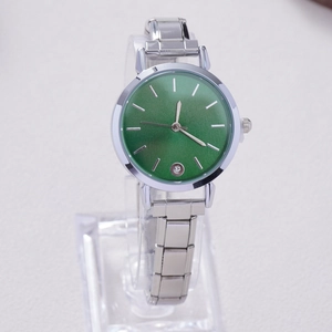 Detail of silver quartz watch featuring a green sunray dial and crystal accent index