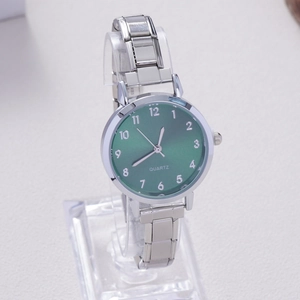 Macro shot of silver quartz watch with emerald green dial and metallic link bracelet