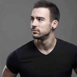 Close-up of minimalist black circular magnetic stud earrings worn by male model