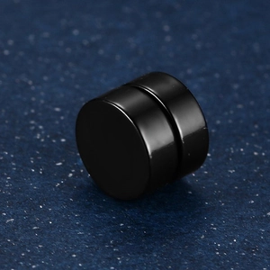 Close-up of minimalist black magnetic stud earring with a glossy polished round finish