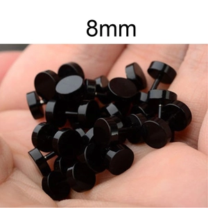 Primer plano de pendientes de barra de 8 mm de acero inoxidable negro en una mano