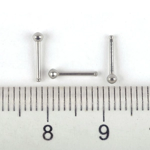 Vista de detalle de tres piercings de nariz de acero de 2mm junto a una regla graduada