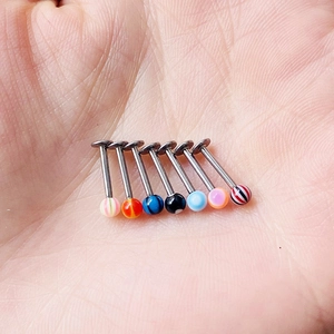 Set of seven colorful acrylic ball labret studs with patterns held in a person's palm
