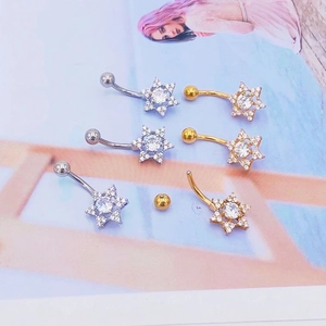 Detalle macro de piercings para ombligo en forma de estrella con circonitas y oro
