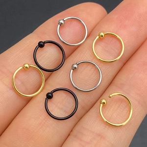 Stainless steel CBR piercing rings in silver, gold, and black finishes on a hand