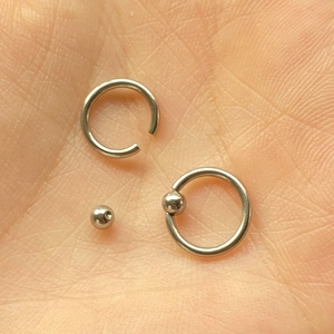 Ensemble d'anneaux de piercing BCR en acier inoxydable argenté posé sur une main