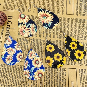 Three-piece sunflower faux leather teardrop earrings set with rustic newspaper background