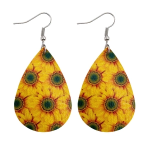 Macro detail of teardrop leather earrings featuring vibrant sunflower floral patterns