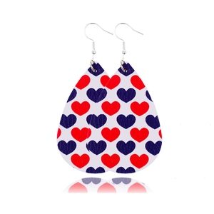 Détail de boucles d'oreilles goutte en similicuir avec motif cœur rouge et bleu sur fond blanc