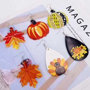 Détail de boucles d'oreilles d'automne avec motifs en cuir de citrouille et feuille d'érable
