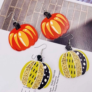 Détail de boucles d'oreilles citrouille en cuir avec paillettes et motifs rayés