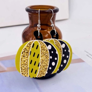 Détail de boucles d'oreilles en cuir avec textures pailletées et motifs citrouille