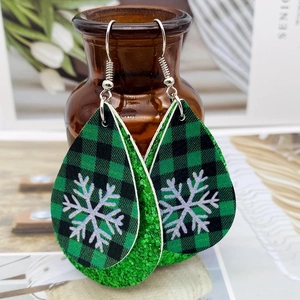 Détail de boucles d'oreilles larmes avec motif flocon à carreaux verts et couche de paillettes