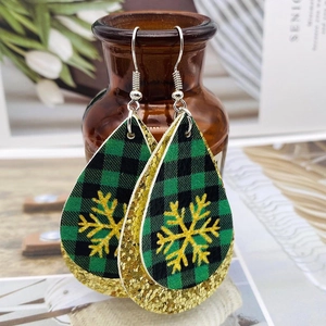 Détail de boucles d'oreilles de Noël à carreaux avec flocons dorés sur un vase brun