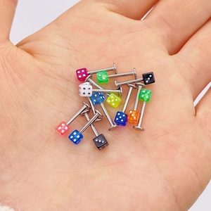 Makroansicht bunter Acryl-Würfel Körperpiercing-Schmuck auf der Hand zum Größenvergleich