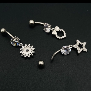 Détail de trois piercings de nombril en acier inoxydable avec pendentifs papillon et étoile