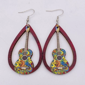 Detailed view of hollow wooden guitar earrings with bohemian paisley art patterns
