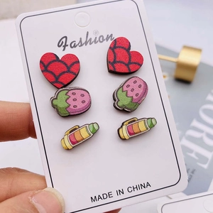 Dettaglio di orecchini a lobo colorati a forma di fragola e cuore su cartoncino fashion