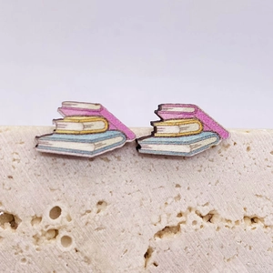 Detailaufnahme von Ohrsteckern in Bücherstapel-Form in Rosa Gelb und Blau auf Stein