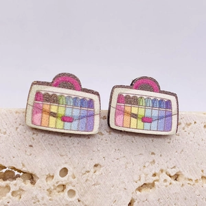 Detailaufnahme der kreativen Regenbogen-Schultaschen-Ohrstecker auf Steinpodest