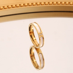 Detailansicht eines Goldrings mit Muscheleinlage und drei glitzernden Zirkonia-Steinen