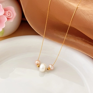 Collar minimalista de titanio dorado con elegantes perlas de agua dulce en plato blanco