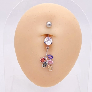 Detalle de piercing de ombligo con circonitas de colores en modelo de piel y fondo blanco