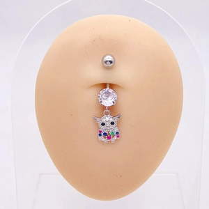 Primer plano de piercing de ombligo de búho con piedras de colores en modelo