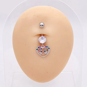 Detalle de piercing de ombligo de acero con colgante de corazón de pájaros y circonitas