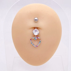 Macro shot of silver belly button ring with a heart pendant and colorful cubic zirconia