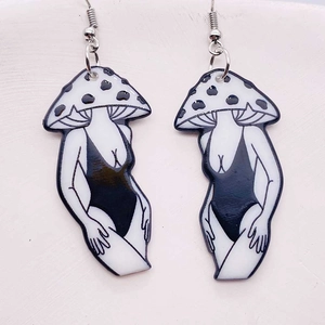 Detailed view of surreal mushroom earrings with monochrome bikini girl figures